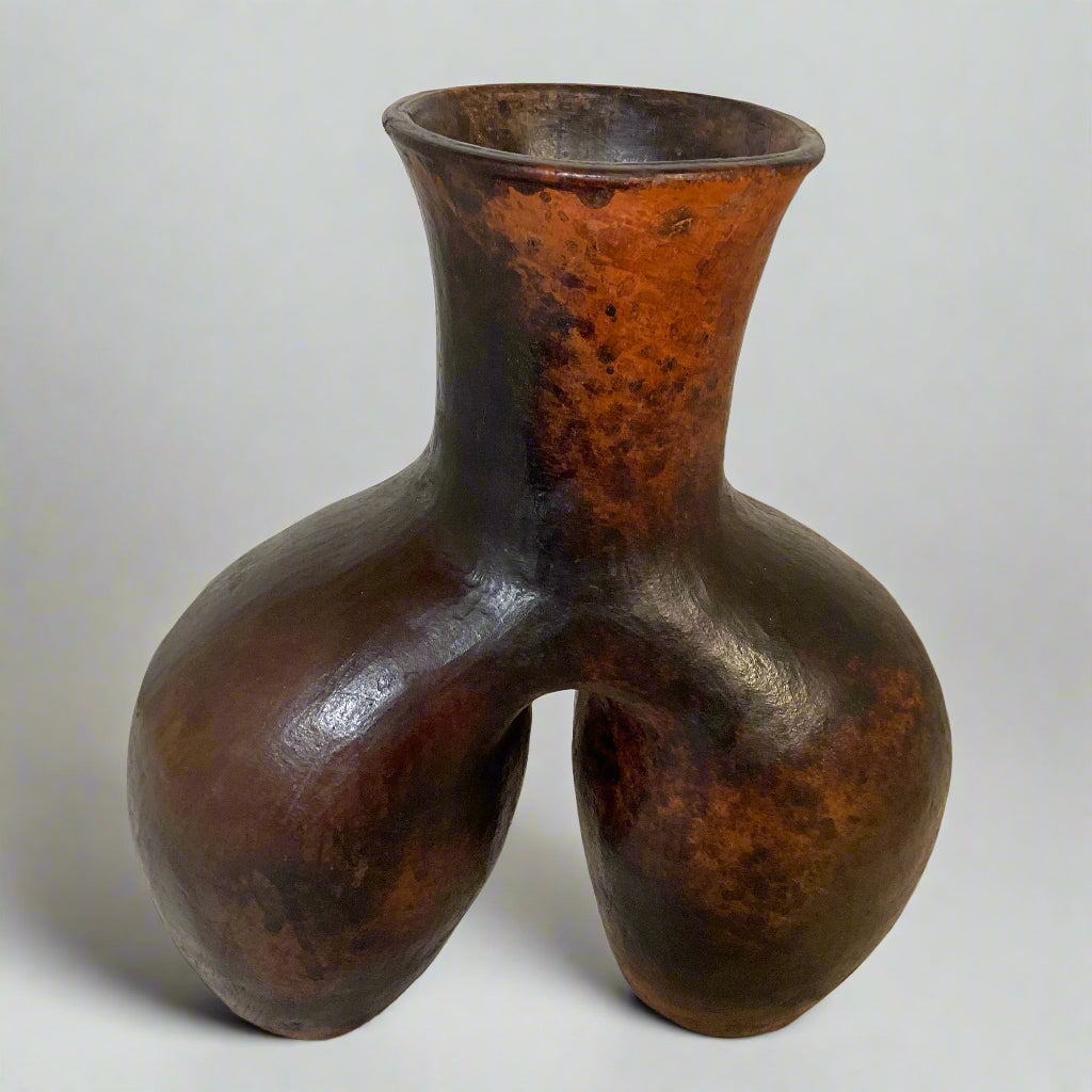 Rustic brown vase on a textured surface with a neutral background