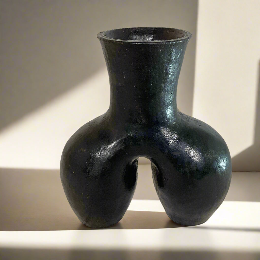 Black vase with unique design on a textured surface