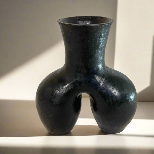 Black vase with unique design on a textured surface