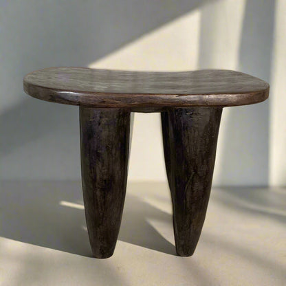 Wooden side table with three legs on a neutral background