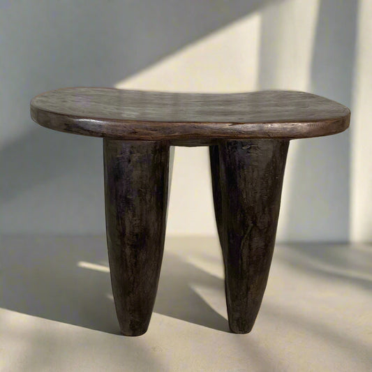 Wooden side table with three legs on a neutral background