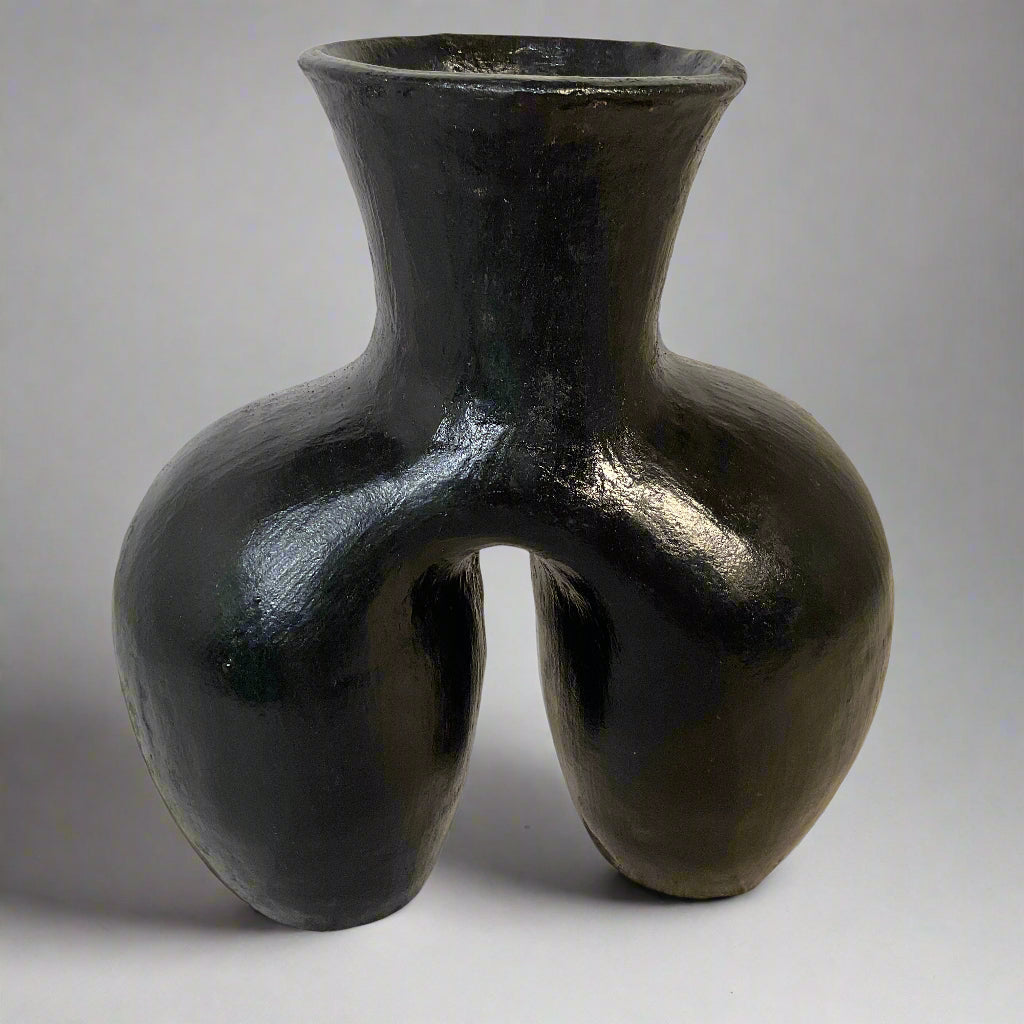 Black vase with a unique design on a textured surface