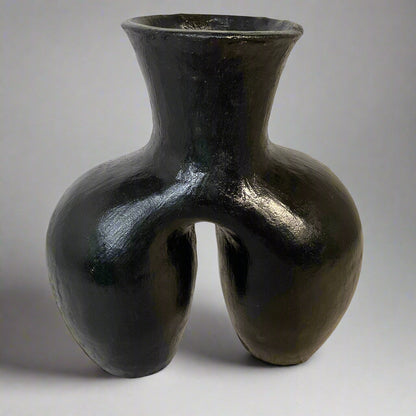 Black vase with a unique design on a textured surface